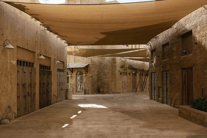 An empty heritage lane runs beneath sand coloured shade sails with a patch of sunlight on the ground.